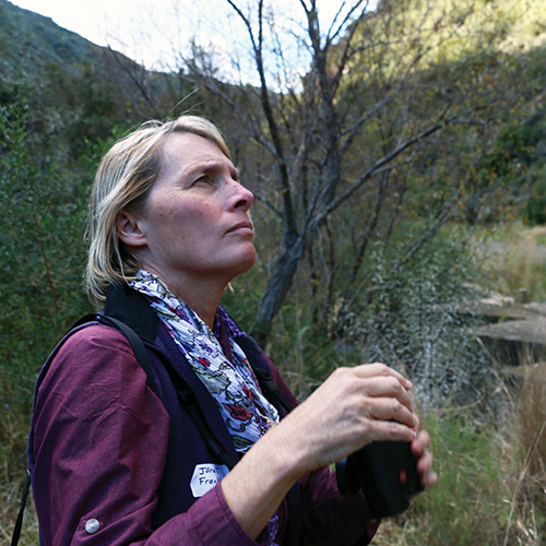 woman holding binoculars looks up